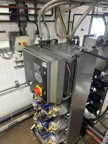 Rear view of custom stainless steel replacement tank installed on a Nilfisk Delta Booster multi-pump pressure washer system.